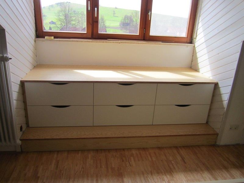 Sitzbank mit Schubladen unter einem Dachschrägenfenster